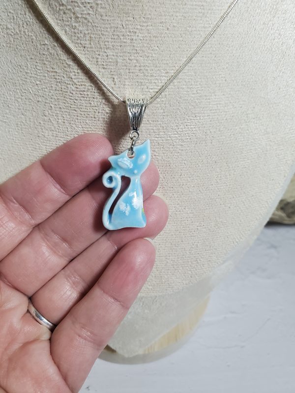 Pendentif en céramique représentant un chat élégant, avec des détails raffinés et une finition lisse, parfait pour les amoureux des félins et les collectionneurs de bijoux uniques.