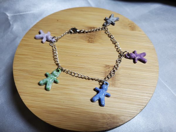 Bracelet artisanal avec figurines en céramique en forme de petits bonhommes, idéal pour un style original et ludique.