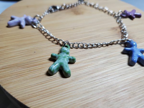 Bracelet artisanal avec figurines en céramique en forme de petits bonhommes, idéal pour un style original et ludique.