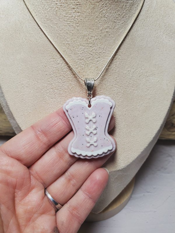 Pendentif élégant en céramique, conçu en forme de corset, avec des détails raffinés et une finition lisse, idéal pour ajouter une touche sophistiquée et unique à votre style.