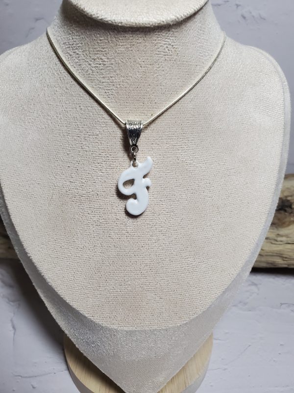 Pendentif artisanal en céramique avec initiale F, bijou élégant et unique.