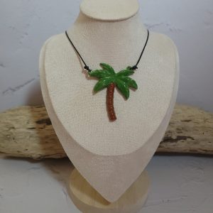 Pendentif délicat en céramique représentant un palmier stylisé, symbole d'évasion et de sérénité. Sa texture artisanale et ses nuances naturelles capturent l'essence des paysages tropicaux.