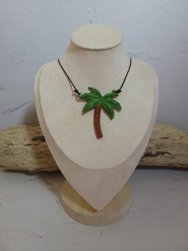 Pendentif délicat en céramique représentant un palmier stylisé, symbole d'évasion et de sérénité. Sa texture artisanale et ses nuances naturelles capturent l'essence des paysages tropicaux.