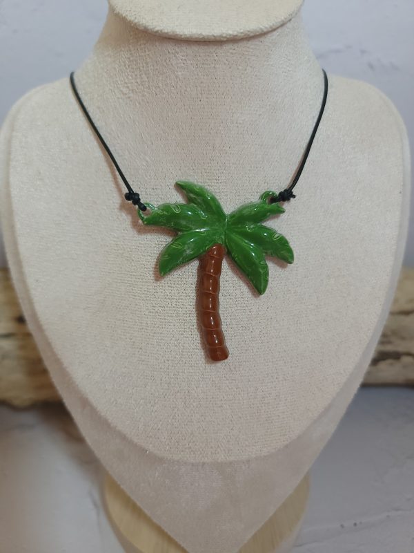 Pendentif délicat en céramique représentant un palmier stylisé, symbole d'évasion et de sérénité. Sa texture artisanale et ses nuances naturelles capturent l'essence des paysages tropicaux.