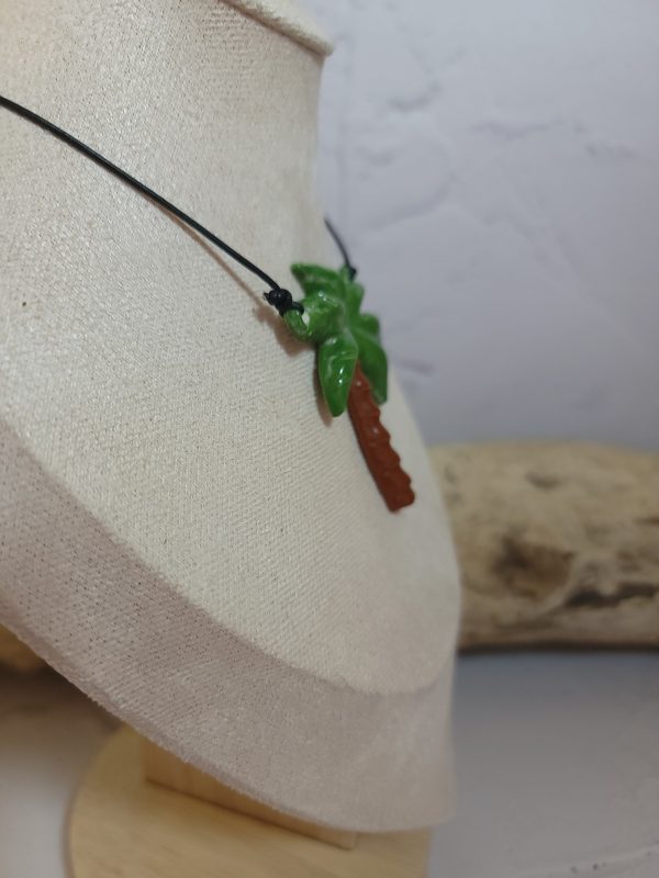 Pendentif délicat en céramique représentant un palmier stylisé, symbole d'évasion et de sérénité. Sa texture artisanale et ses nuances naturelles capturent l'essence des paysages tropicaux.