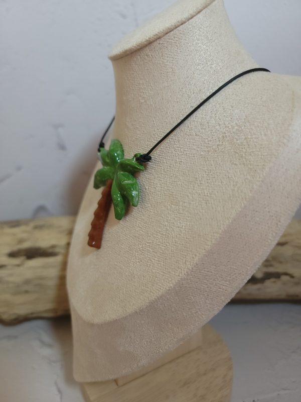 Pendentif délicat en céramique représentant un palmier stylisé, symbole d'évasion et de sérénité. Sa texture artisanale et ses nuances naturelles capturent l'essence des paysages tropicaux.
