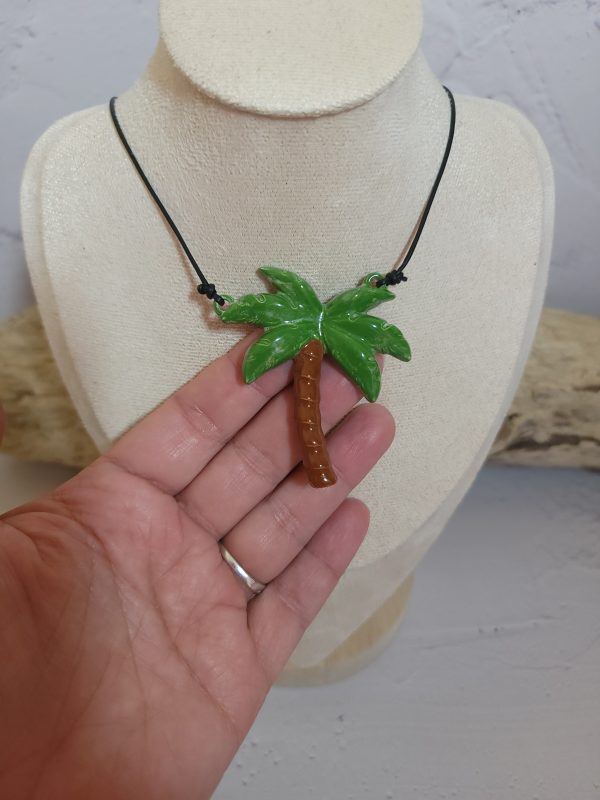 Pendentif délicat en céramique représentant un palmier stylisé, symbole d'évasion et de sérénité. Sa texture artisanale et ses nuances naturelles capturent l'essence des paysages tropicaux.