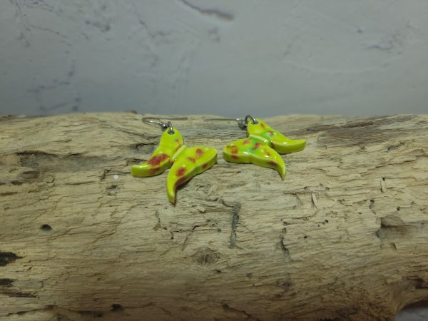 Élégantes boucles d'oreilles en céramique façonnées en forme de papillon, avec des détails délicats et une finition brillante qui reflète la lumière avec douceur.