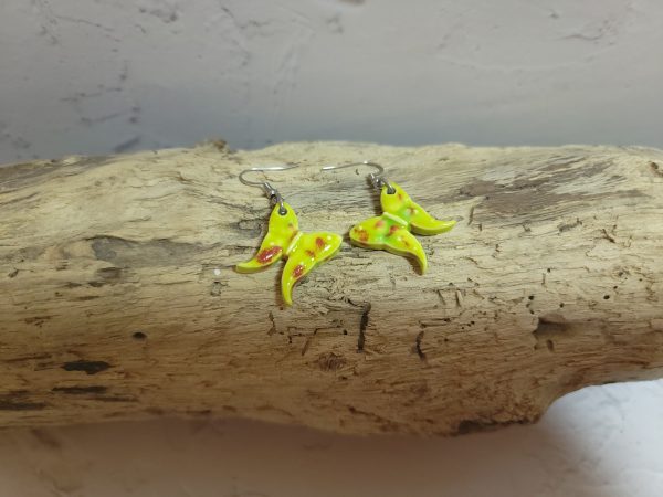 Élégantes boucles d'oreilles en céramique façonnées en forme de papillon, avec des détails délicats et une finition brillante qui reflète la lumière avec douceur.