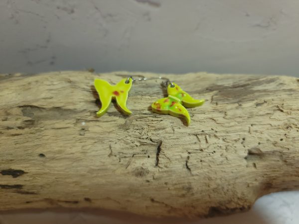 Élégantes boucles d'oreilles en céramique façonnées en forme de papillon, avec des détails délicats et une finition brillante qui reflète la lumière avec douceur.