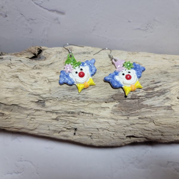 Boucles d’oreilles artisanales en céramique représentant une tête de clown souriant, aux couleurs vives et au style fantaisiste.