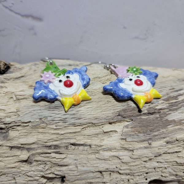 Boucles d’oreilles artisanales en céramique représentant une tête de clown souriant, aux couleurs vives et au style fantaisiste.