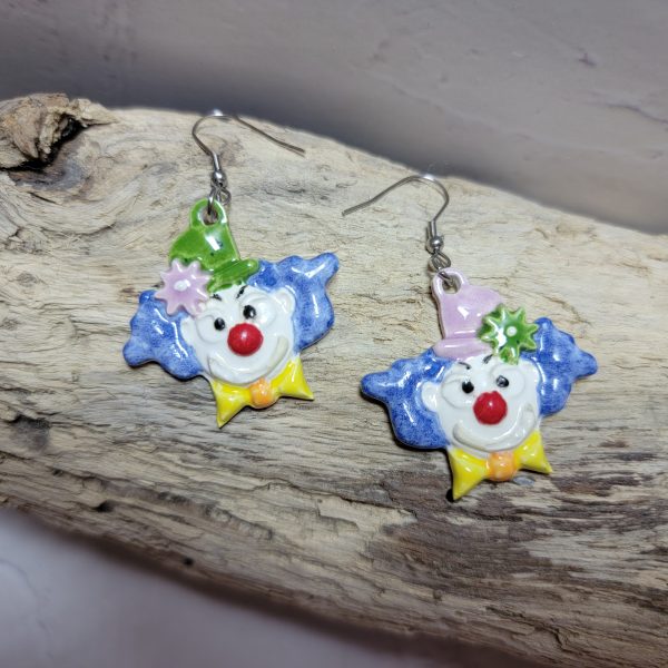 Boucles d’oreilles artisanales en céramique représentant une tête de clown souriant, aux couleurs vives et au style fantaisiste.