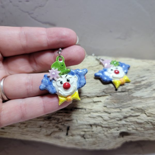Boucles d’oreilles artisanales en céramique représentant une tête de clown souriant, aux couleurs vives et au style fantaisiste.